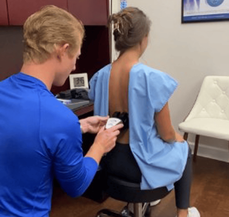Dr. Leo Ruettiger performing a spinal scan during a new patient exam at Charleston Chiropractic Studio in Charleston, SC